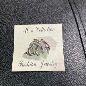 Adorable pin of two dolphins adorned with diamond- like stones.